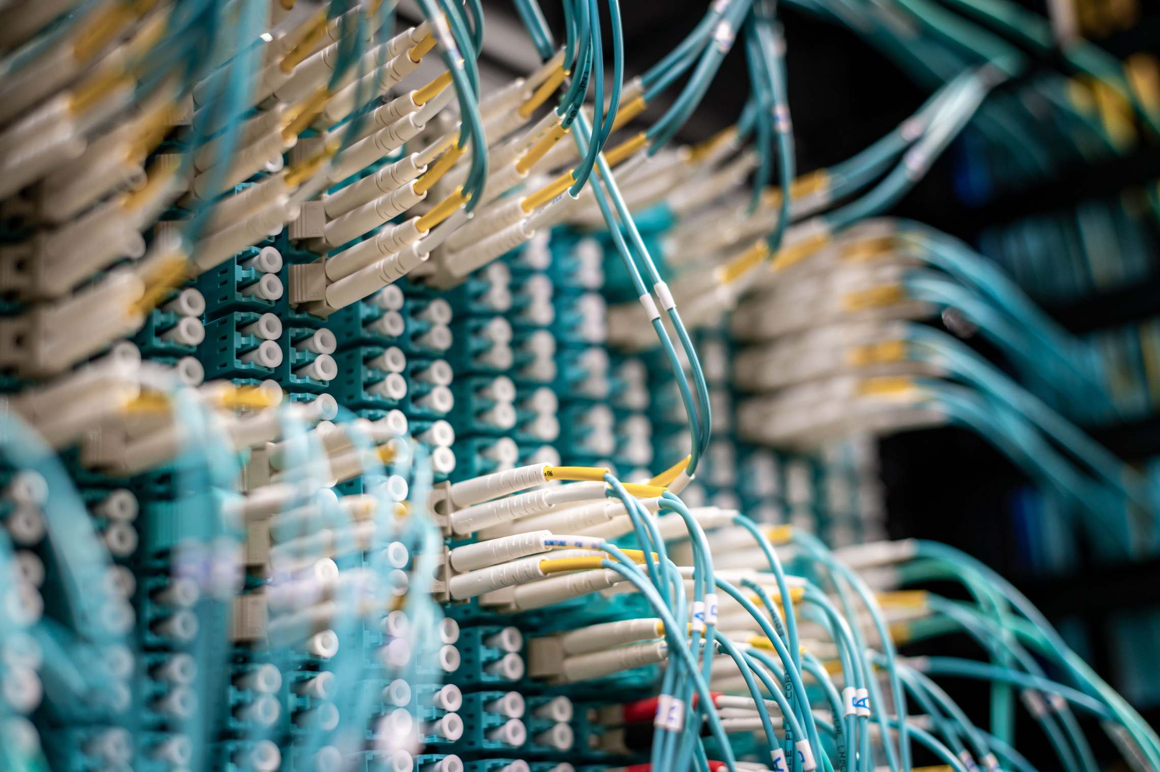 Rows of network servers and cabling in a data hall, fiber optic switch with connected cables