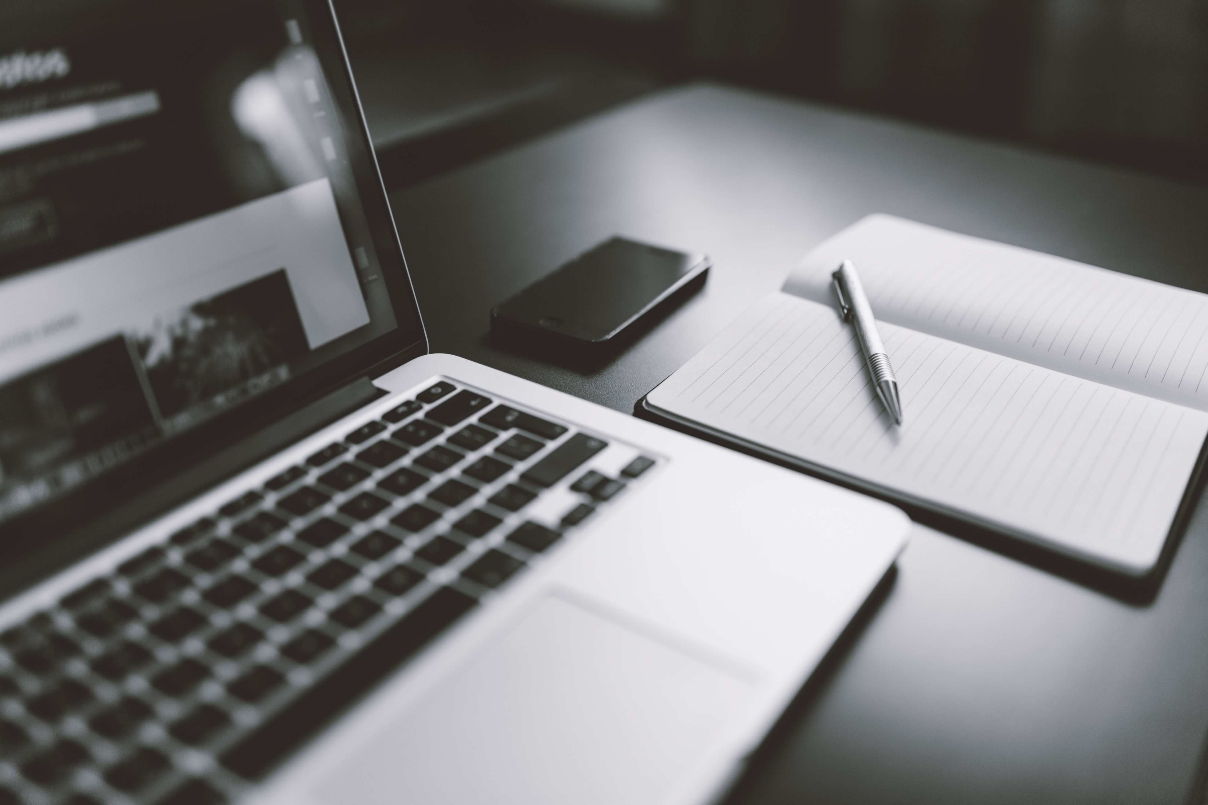Laptop beside a paper notebook used for pipeline notes, notebook with a pen